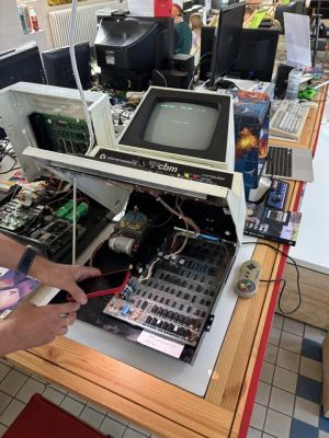 Geöffneter Commodore CBM Computer mit sichtbarer Platine und rotem Smartphone davor.