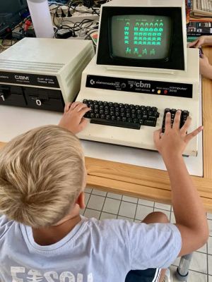 Blonder Junge spielt ein Retro-Spiel auf einem vintage Commodore CBM 3016 Computer.